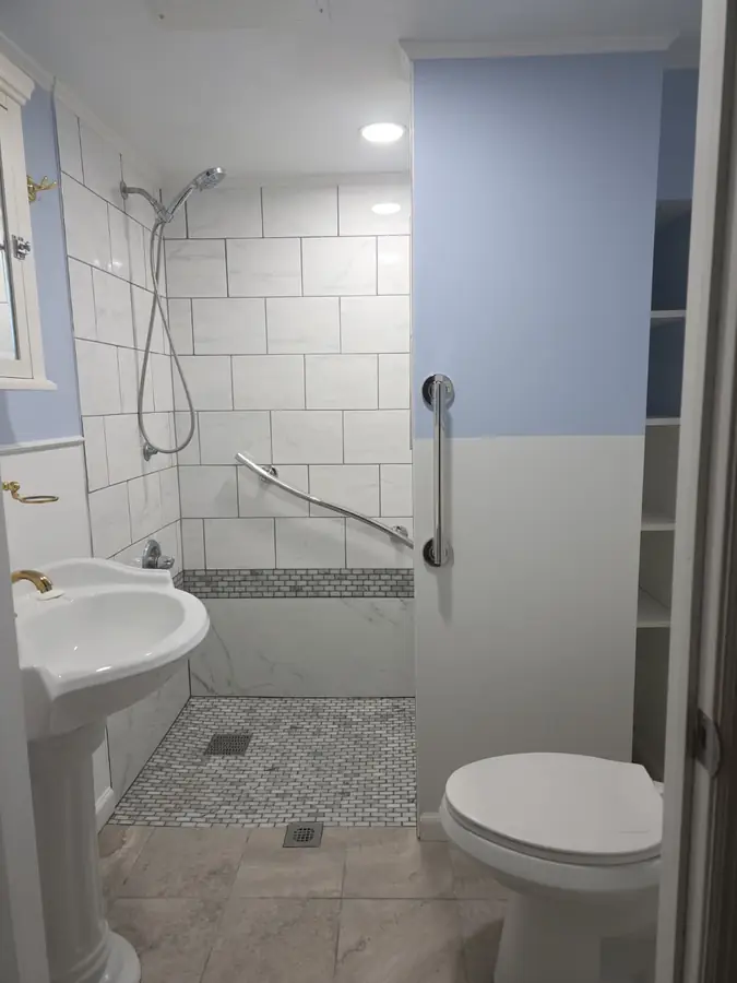 Finished curbless walk-in shower with bench, mosaic floor and grab bars